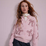 Cardigan rosa chiaro con fiocchi di lana morbida e bottoni frontali indossato da bambina