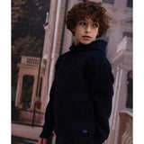 Maglione con cappuccio blu scuro indossato da bambino con capelli ricci in ambiente urbano